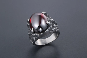 Gros plan d'une bague rétro en argent avec gemme rouge ovale et gravures en écailles