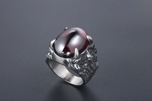 Détail d'une bague vintage sertie d'une gemme rouge avec griffes de dragon et textures écailles