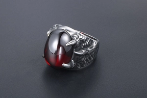 Détail d'une bague griffe de dragon en argent avec une large pierre précieuse rouge foncé