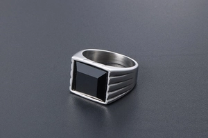 Dettaglio anello da uomo in metallo argento con pietra nera quadrata e trama a gradini