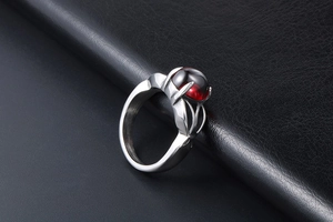 Macro detail of silver stainless steel ring featuring a round deep red gemstone cabochon