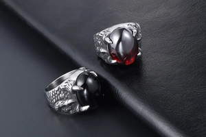 Détail de bagues gothiques en griffe de dragon avec pierres rouge et noir sur cuir
