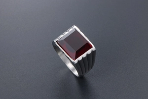 Dettaglio di pietra rossa rettangolare su anello in acciaio titanio con scanalature
