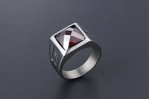 Close-up of vintage titanium steel signet ring with square red gemstone and textured sides