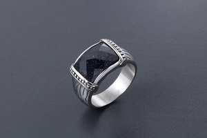 Détail d'une bague en titane avec pierre de soleil bleue carrée et reliefs ciselés
