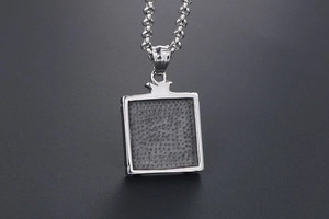 Detail of square titanium steel pendant with crown clasp and grey honeycomb texture
