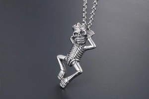 Detailed view of a silver crown skull skeleton pendant on a heavy metal chain