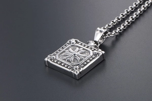 Macro detail of square stainless steel pendant with embossed cross pattern and round link chain