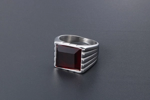 Vista macro di un anello da uomo con pietra rossa quadrata e acciaio spazzolato