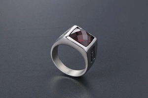Detail view of vintage signet ring with red square gemstone and engraved steel band