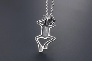 Macro view of silver frog pendant showing detailed matte finish and metallic texture