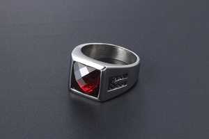 Macro view of vintage steel ring featuring square red gemstone and brushed metal texture