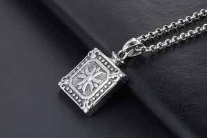 Macro shot of square titanium steel pendant with embossed cross flower and rolo chain