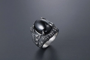 Macro shot of punk dragon claw ring with black gemstone and vintage steel finish