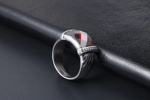 Gros plan d'une bague rétro pour homme avec pierre rouge facettée et acier brossé