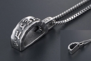 Macro shot of titanium steel Buddhist pendant with Om Mani Padme Hum relief details