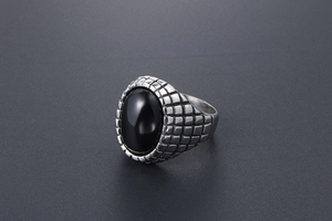 Macro shot of men's vintage silver ring with oval black onyx and grid texture