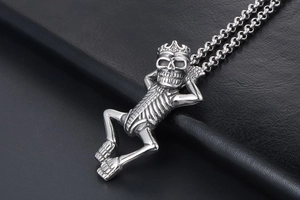 Detail shot of a gothic silver skeleton pendant with crown on black leather