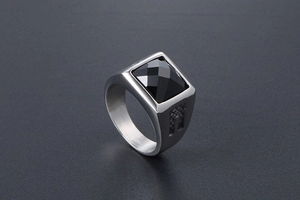 Detailed macro view of silver steel ring featuring square cut black gemstone with texture