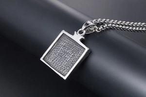 Detail shot of rectangular stainless steel pendant with textured center and rolo chain