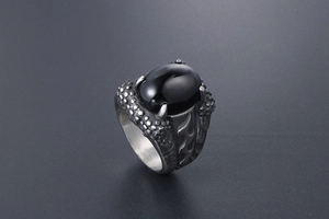 Detail view of gothic dragon claw ring with black gemstone and vintage steel texture