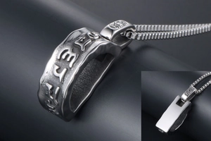 Macro detail of silver stainless steel pendant with engraved mantras and box chain