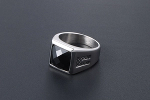 Macro detail of men's signet ring featuring a large faceted black gemstone and steel texture