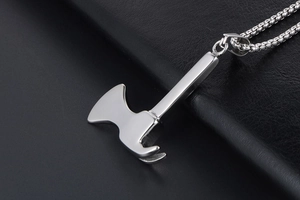 Detail shot of a polished silver axe pendant on a bead chain over black leather background