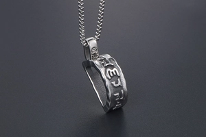 Close-up of titanium steel pendant with embossed Buddhist mantras and hammered texture