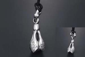 Detail of silver cross pendant with intricate embossed bell shape on black cord