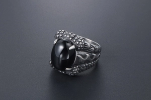 Macro detail of men's dragon claw ring featuring a large oval black gemstone inlay