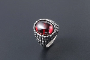 Detail view of a vintage men's ring with a large red oval stone and textured silver band