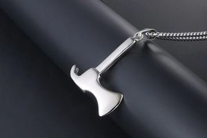 Macro shot of silver axe pendant necklace on a dark cylindrical display stand