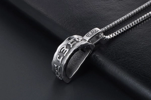 Macro view of religious pendant with embossed mantra symbols and box chain for men