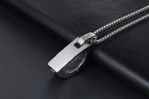 Macro detail of gothic style engravings on stainless steel pendant with box chain