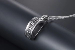 Detailed view of silver stainless steel pendant with etched mantra and hammered texture