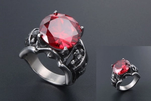 Gros plan sur une bague gothique en acier titane avec rubis rouge et crânes sculptés