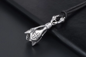 Macro shot of punk style lotus pendant with cross relief on braided black rope
