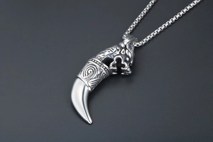 Detail of vintage wolf head pendant with polished fang on heavy metal box chain