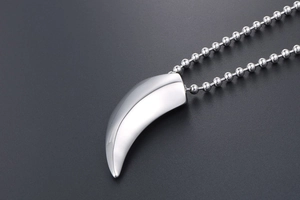 Macro d'un pendentif dent de loup en argent avec chaîne à billes polie sur fond gris foncé