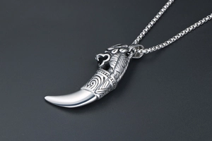 Macro shot of a retro silver wolf tooth pendant with tribal patterns and box chain
