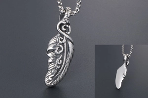 Close-up of feather pendant showing relief carvings and polished steel back details