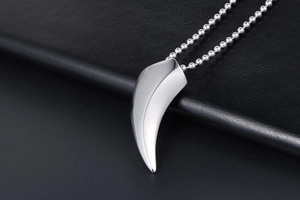 Vue macro d'un pendentif en forme de dent en acier poli sur une chaîne à billes argentée