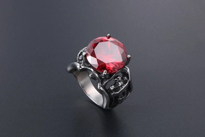 Gros plan d'une bague gothique avec une grande pierre rouge et des gravures ciselées
