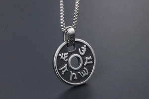 Détail macro du pendentif circulaire en acier titane avec caractères de mantra bouddhiste