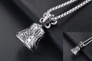 Detailed macro of vintage bell pendant featuring fleur-de-lis and cross relief patterns