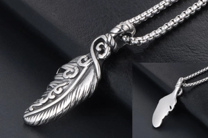 Detailed macro view of silver feather pendant with intricate cloud engravings and box chain