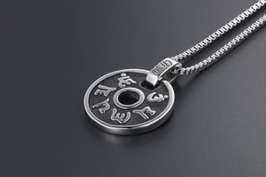 Détail macro du pendentif circulaire en acier argenté avec gravure Sanskrit vintage