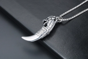 Detailed macro view of vintage silver wolf tooth pendant with engraved animal motif