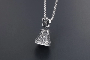 Macro shot of gothic bell pendant with fleur-de-lis and cross engraving in vintage silver